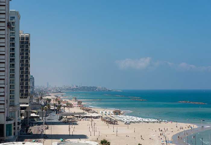 Tel Aviv beach view from Leonardo Art Hotel, a gay-friendly hotel by the beach. Sandy shore, blue sea, and city skyline.