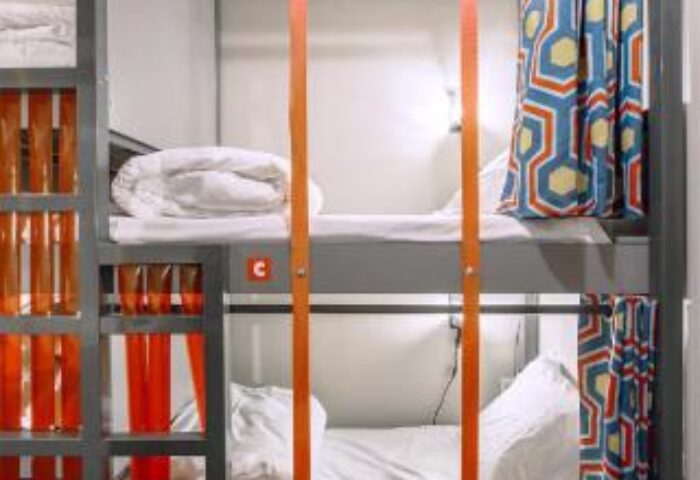 Les Piaules gay-friendly hotel: Bunk beds in a hostel room. Colorful curtains and orange straps. Modern design at The People hostel.