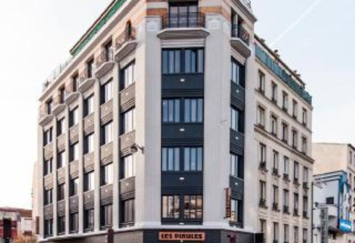 Exterior of Les Piaules, a gay-friendly hotel in Paris. Modern building on a street corner, perfect for gay men travel advice.