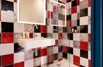 Les Tournelles gay-friendly hotel bathroom. Modern square tile design in red, white, and black. Sink, mirror, and shower.