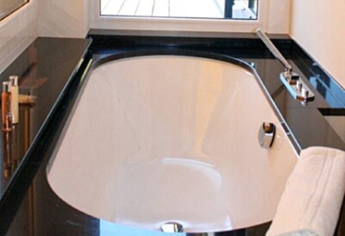 Bathtub at LiV'iN Residence Frankfurt Seilerstraße, a gay-friendly hotel. Features a black countertop and modern fixtures. Ideal for gay travel.