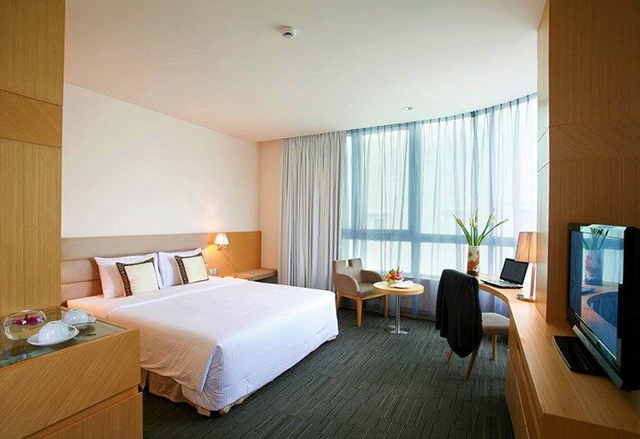 Liberty Central Saigon Centre Hotel's bedroom. Gay-friendly hotel in Ho Chi Minh City. Modern room with desk, TV, and large window.