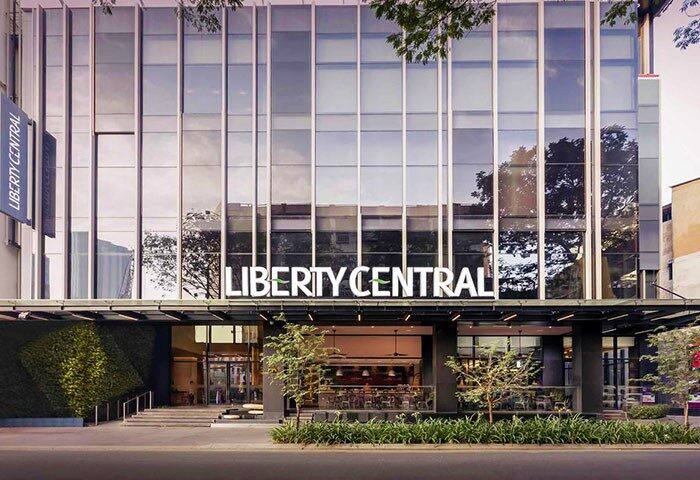 Facade of Liberty Central Saigon Citypoint Hotel, a gay-friendly hotel in Ho Chi Minh City. Modern architecture, glass windows, and greenery.