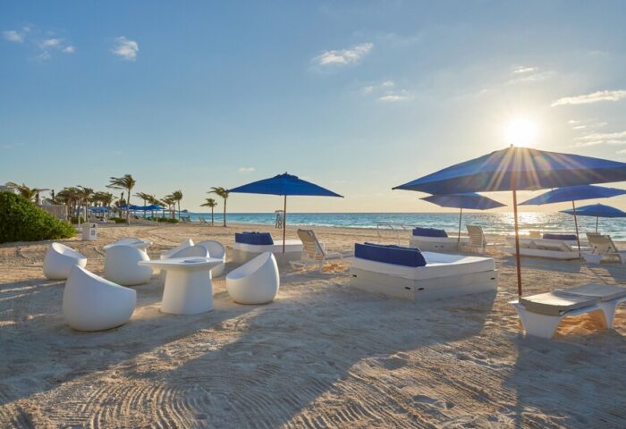 Beachfront view at Live Aqua Beach Resort Cancun, an all-inclusive, adults-only, gay-friendly hotel. Lounge chairs and umbrellas on the sand.