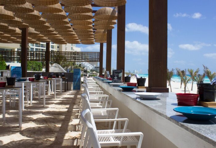 Live Aqua Beach Resort Cancun adults-only all-inclusive gay-friendly hotel. Beachside restaurant with tables and chairs overlooking the ocean.