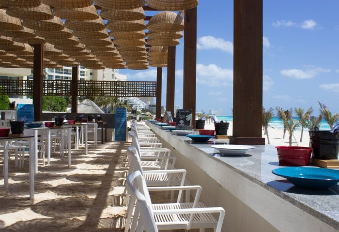 Live Aqua Beach Resort Cancun adults-only all-inclusive gay-friendly hotel. Beachside restaurant with tables and chairs overlooking the ocean.