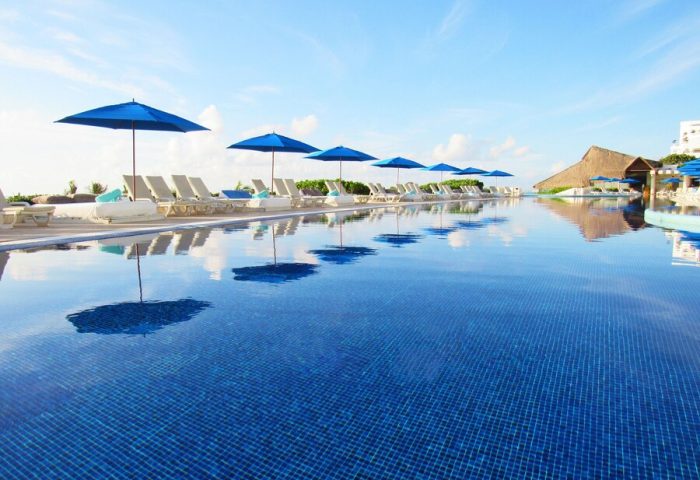 Live Aqua Beach Resort Cancun pool view. Adults-only, all-inclusive, gay-friendly hotel. Blue umbrellas and lounge chairs.
