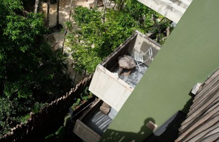 Aerial view of a balcony at Loba Tulum Male Only, a gay-friendly hotel. Lush greenery surrounds the modern architecture.