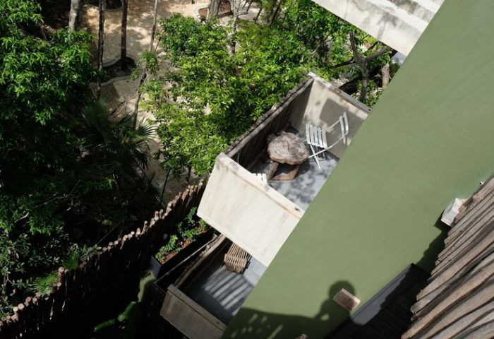 Aerial view of a balcony at Loba Tulum Male Only, a gay-friendly hotel. Lush greenery surrounds the modern architecture.