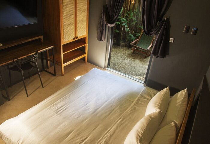 Loba Tulum Male Only room. Bed, desk, and wardrobe inside, plus a view of the outdoor patio. Gay-friendly hotel room interior.