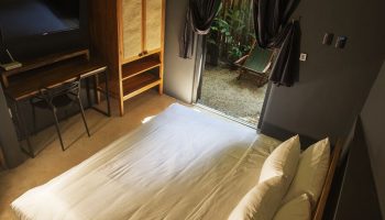 Loba Tulum Male Only room. Bed, desk, and wardrobe inside, plus a view of the outdoor patio. Gay-friendly hotel room interior.