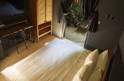 Loba Tulum Male Only room. Bed, desk, and wardrobe inside, plus a view of the outdoor patio. Gay-friendly hotel room interior.