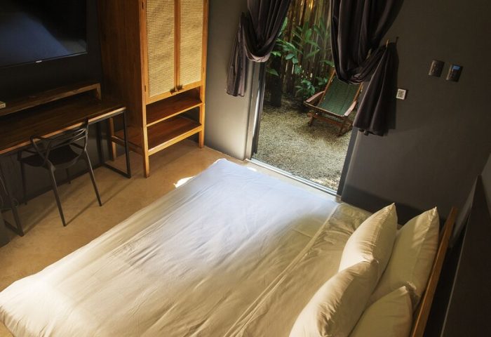 Loba Tulum Male Only room. Bed, desk, and wardrobe inside, plus a view of the outdoor patio. Gay-friendly hotel room interior.