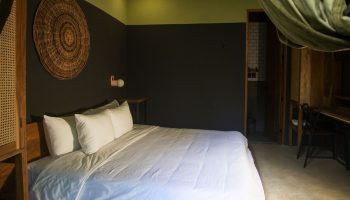Loba Tulum Male Only gay-friendly hotel room. King bed, dark walls, woven wall art, desk, and bathroom. Modern design for gay travelers.