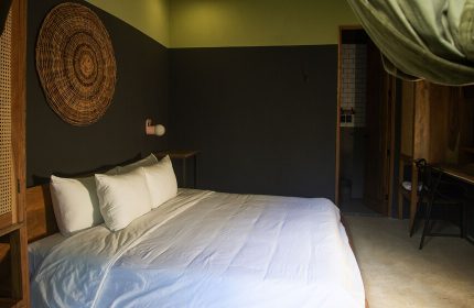 Loba Tulum Male Only gay-friendly hotel room. King bed, dark walls, woven wall art, desk, and bathroom. Modern design for gay travelers.