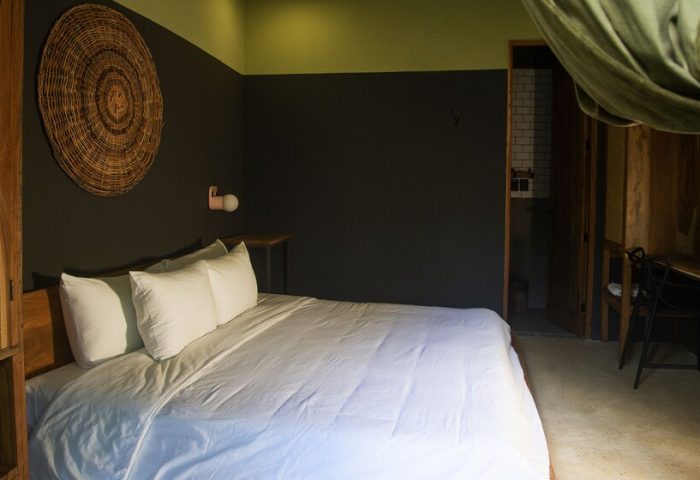Loba Tulum Male Only gay-friendly hotel room. King bed, dark walls, woven wall art, desk, and bathroom. Modern design for gay travelers.