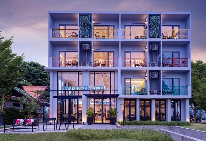 Lub D Koh Samui Chaweng Beach hotel facade. Gay-friendly hotel with colorful balconies. Modern architecture, greenery, and inviting entrance.