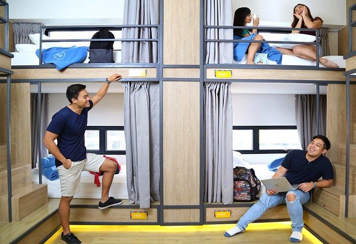 Lub D Philippines Makati hostel dorm room. Gay-friendly hotel with bunk beds, curtains, and travelers relaxing. Modern, clean design.