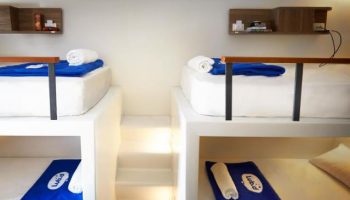 Lub d Phuket Patong gay-friendly hotel room. Modern bunk beds with blue towels and linens. Steps lead to the upper bunks. Shelves.