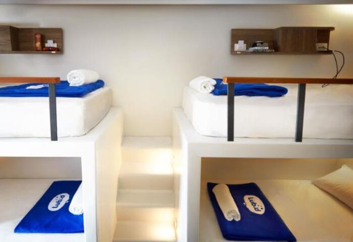 Lub d Phuket Patong gay-friendly hotel room. Modern bunk beds with blue towels and linens. Steps lead to the upper bunks. Shelves.