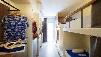 Lub d Phuket Patong gay-friendly hotel: dormitory room interior with bunk beds, clothes, and a bag. A modern, budget-friendly stay.