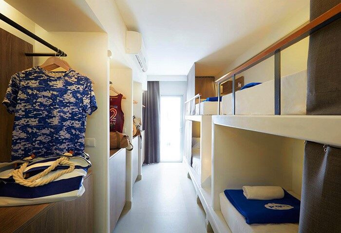 Lub d Phuket Patong gay-friendly hotel: dormitory room interior with bunk beds, clothes, and a bag. A modern, budget-friendly stay.