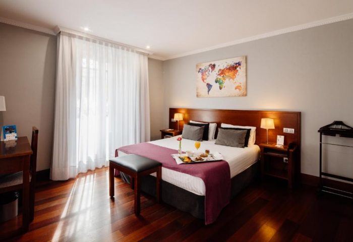 Hotel Infantas by MIJ, a gay-friendly luxury hotel. Room with double bed, breakfast tray, desk, and world map art. Pet-friendly stay.