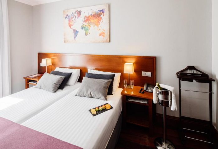 Hotel Infantas by MIJ, a gay-friendly, luxury, pet-friendly room. Twin beds, champagne, fruit, and a world map create a welcoming space.
