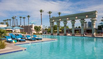 Luxor Hotel pool, a gay-friendly hotel. Turquoise water, palm trees, and Egyptian-themed architecture. Ideal for gay travel in Las Vegas.