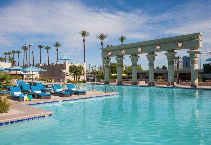 Luxor Hotel pool, a gay-friendly hotel. Turquoise water, palm trees, and Egyptian-themed architecture. Ideal for gay travel in Las Vegas.