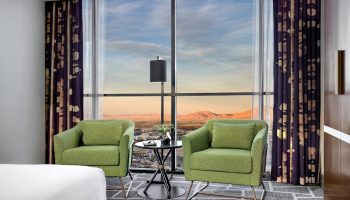 Luxor Hotel room with a view. Two green chairs face a large window overlooking the Las Vegas strip. Gay-friendly hotel for travel advice.