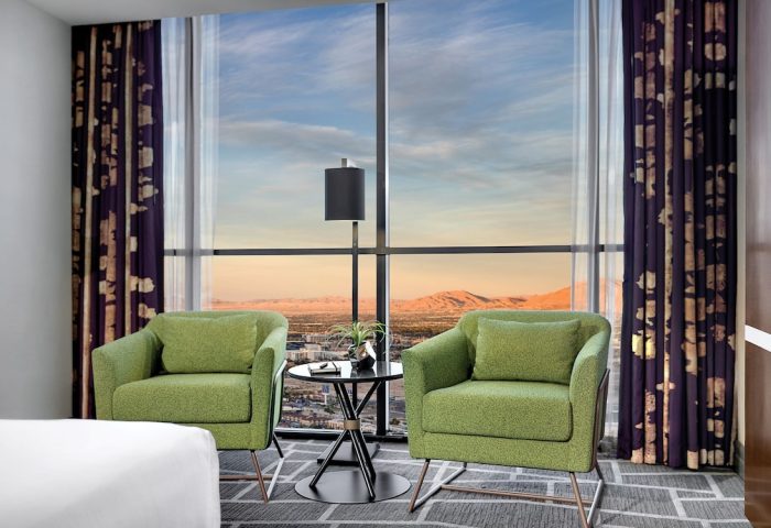 Luxor Hotel room with a view. Two green chairs face a large window overlooking the Las Vegas strip. Gay-friendly hotel for travel advice.