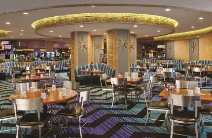 Interior of the Luxor Hotel, a gay-friendly hotel. Tables and chairs are set for dining, with Egyptian-themed decor. Las Vegas travel.