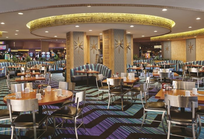Interior of the Luxor Hotel, a gay-friendly hotel. Tables and chairs are set for dining, with Egyptian-themed decor. Las Vegas travel.