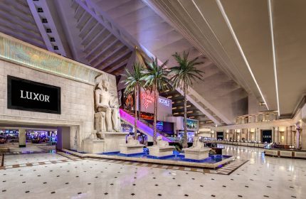 Luxor Hotel interior. Gay-friendly hotel with Egyptian theme, statues, palm trees, and pyramid architecture. Las Vegas travel advice.