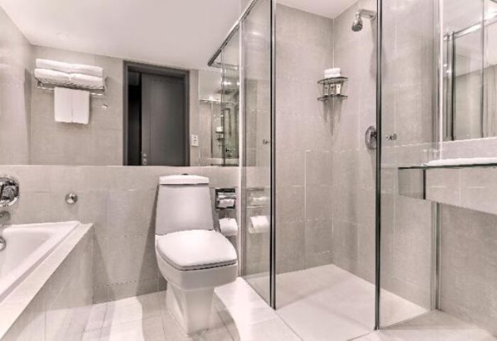Bathroom at M Hotel, a gay-friendly hotel. Features a toilet, bathtub, shower with glass door, and modern fixtures. Ideal for gay travel.