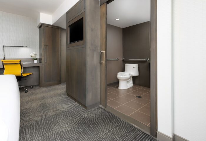 M Social Times Square gay-friendly hotel room. Accessible bathroom with handrails, desk, and TV. Modern design for gay men travelers.