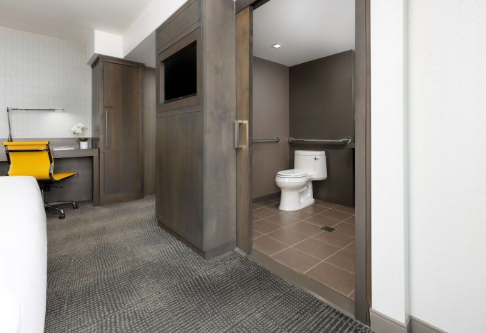 M Social Times Square gay-friendly hotel room. Accessible bathroom with handrails, desk, and TV. Modern design for gay men travelers.