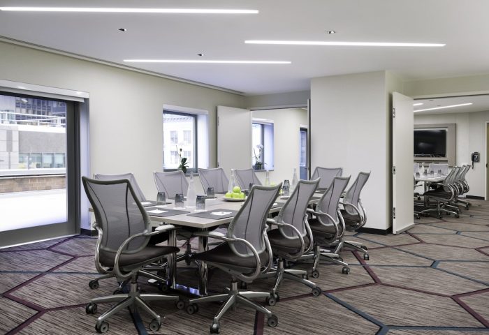 M Social Times Square gay-friendly hotel meeting room. Conference table with chairs, water, and apples. Modern design. Business travel.