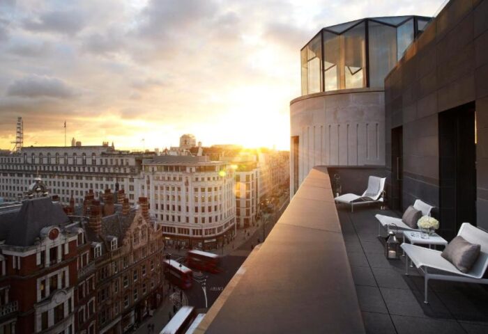 Rooftop view from ME London Hotel, a gay-friendly, pet-friendly hotel. Sunset over London skyline, chairs on terrace. Luxury travel for gay men.