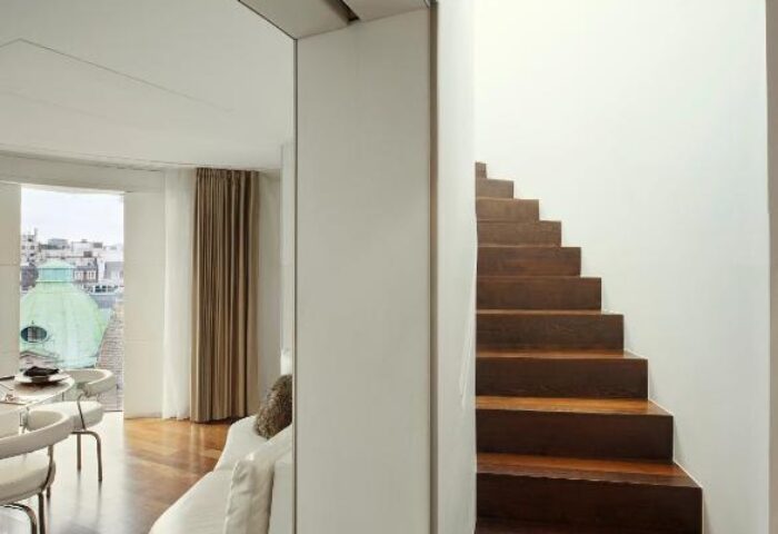 ME London Hotel interior: Stairs, white sofa, and dining area with a view. Gay-friendly, pet-friendly hotel.