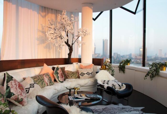 Gay-friendly ME London Hotel pet-friendly suite. Luxury room with city view, sofa, pillows, and stylish decor. Ideal for gay travel.