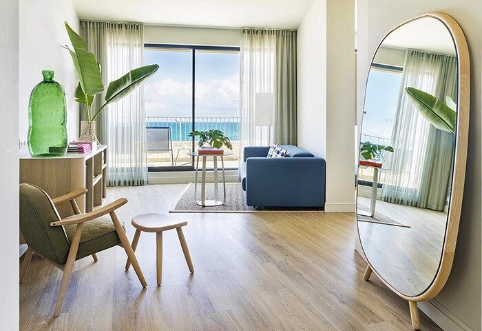 ME Sitges Terramar gay-friendly hotel room. Interior view with balcony, sea view, sofa, chair, and mirror. Pet-friendly hotel.