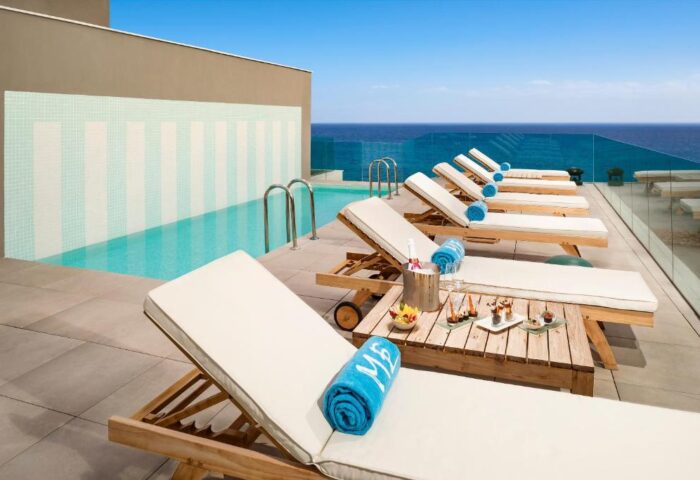 ME Sitges Terramar gay-friendly hotel pool. Loungers, snacks, and champagne bucket. Pet-friendly hotel with ocean view.
