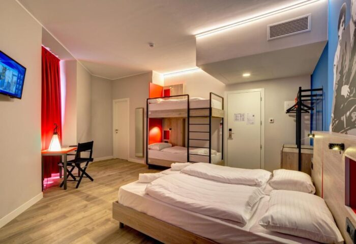 MEININGER Roma Termini gay-friendly hotel room. Features a double bed, bunk beds, desk, and TV. Great for gay travelers in Rome.