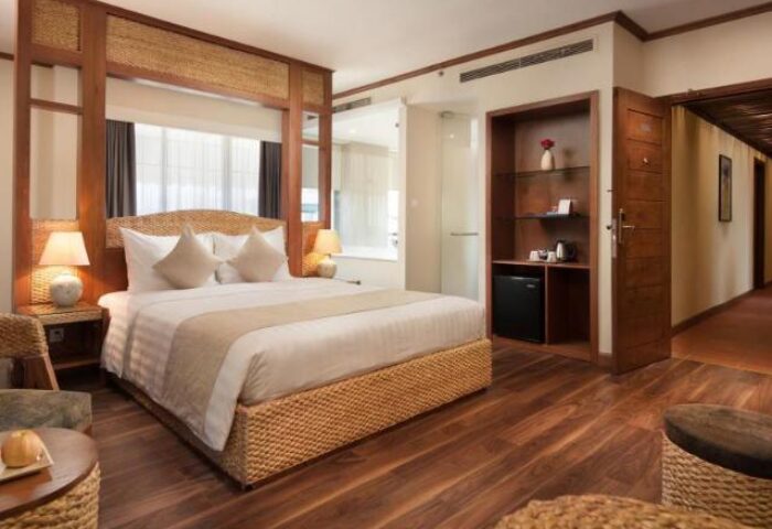 MK Premier Boutique Hotel room. Gay-friendly hotel with a bed, wooden floor, and a view of the bathroom. Ideal for gay travel.