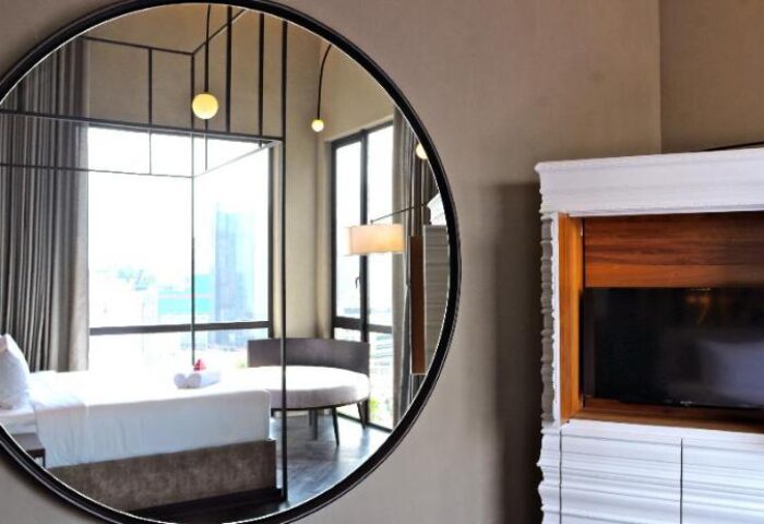 MOV Hotel gay-friendly room: Round mirror reflecting a bed, chair, and city view. Modern design, elegant decor, ideal for gay travelers.