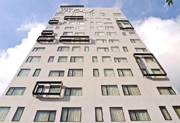 Exterior of MOV Hotel, a gay-friendly hotel with many windows and some balconies. The MOV logo is at the top of the building.