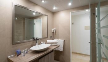 Bathroom at MS Aguamarina Suites, a gay-friendly hotel. Features a modern sink, mirror, and shower. Great for gay travel.
