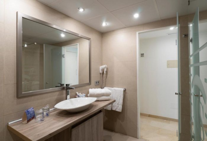 Bathroom at MS Aguamarina Suites, a gay-friendly hotel. Features a modern sink, mirror, and shower. Great for gay travel.